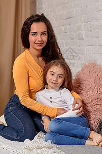 对年轻母亲和女儿的爱他们坐在家里的床上玩得开心图片