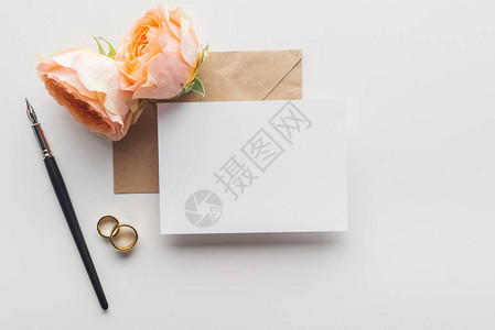 棕色手工艺纸袋墨笔玫瑰和灰色背景的金结婚戒指上图片
