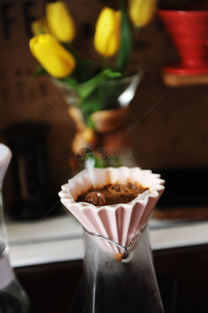 在粉红色陶瓷滴水器中用纸过滤器酿制替代咖啡背景上的黄图片