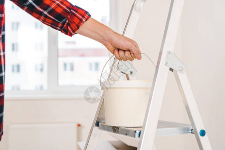 人用梯子手握着油漆桶的图片