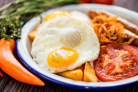 烤鸡蛋香肠番茄和洋葱环的紧贴盘子图片