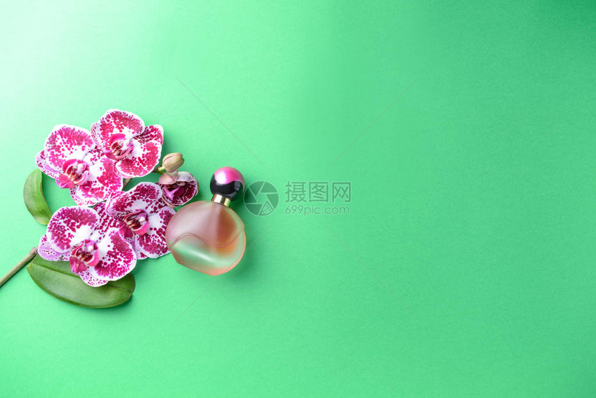 美丽的兰花和彩色背景上的香水瓶图片
