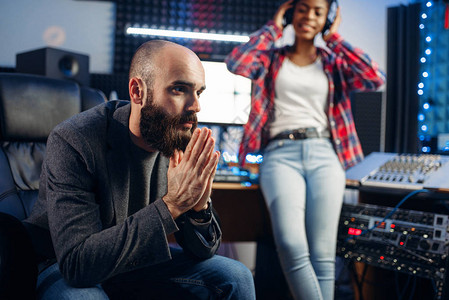 耳语音响制作人和女歌手在录音室监听曲目专业的音频和音乐混合图片