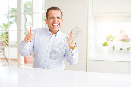 中年男子坐在家里成功标志用手做积极的手势图片
