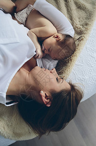 年轻母亲拥抱躺在床上的新生女图片