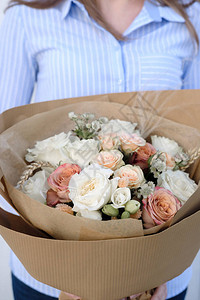 白色和米色玫瑰花束女花店拿着一束鲜花在室内女花店在花店准备花束特写母亲节图片