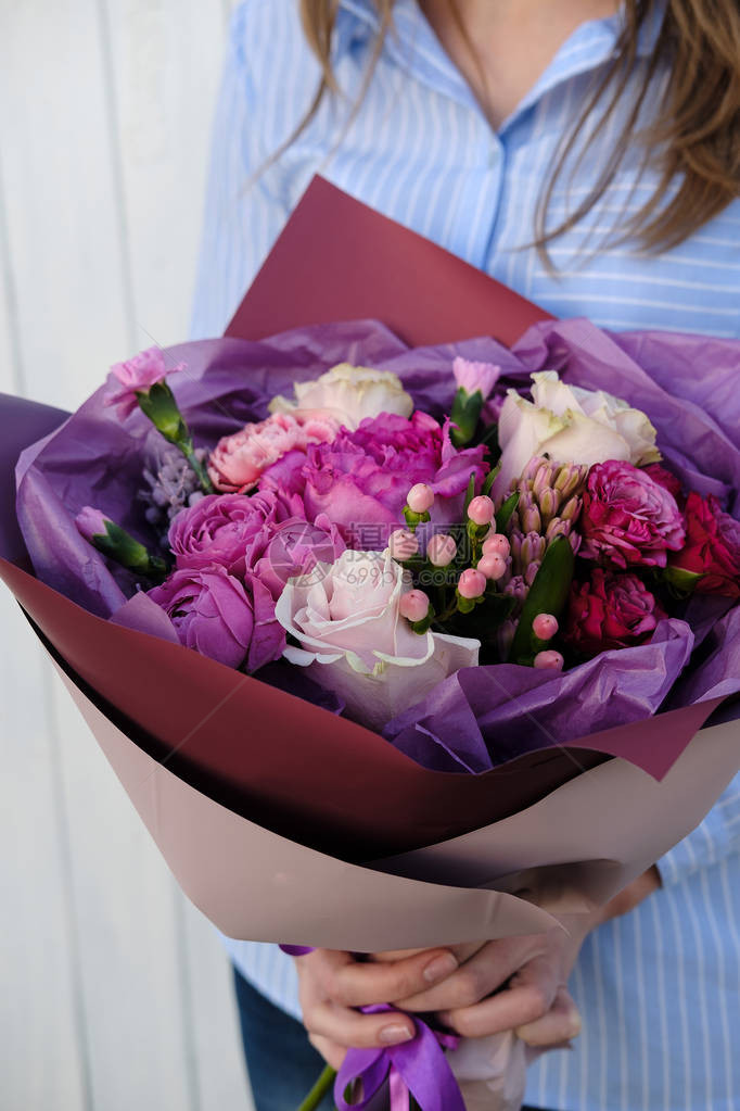 粉红色和紫色的玫瑰花束女人花店捧着一束鲜花室内女花店在花店准备花束特写母亲节图片
