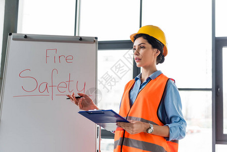身戴头盔手持剪贴板和笔的女消防员图片