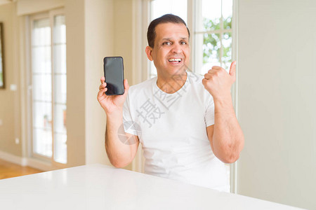 中年男子显示智能手机屏幕指向并用大拇指举起手指向另一边图片