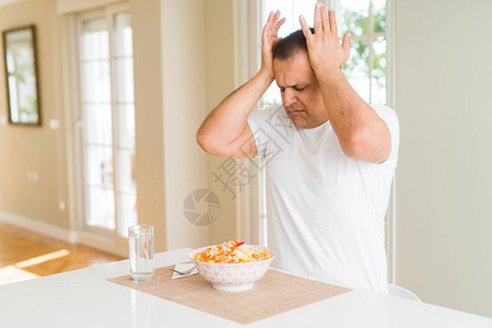 在家吃米饭的中年男子因疼痛和偏头痛而头痛绝望和压力大图片