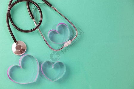 世界卫生日背景绿色背景上的听诊器和粉红丝带心概念保图片