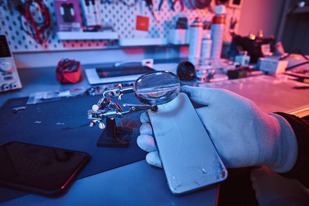 电子技术人员拿着一部机身破损的现代智能手机图片