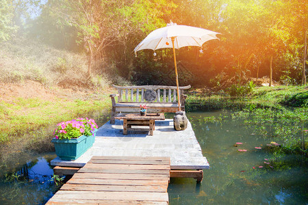 夏季在水池和配有雨伞的桌边露台花园和木图片