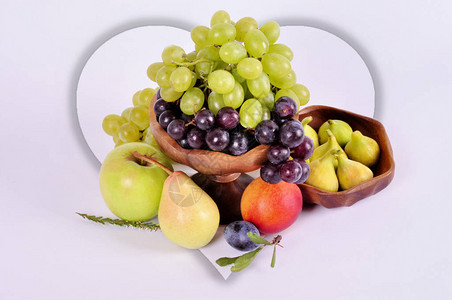浅色和深色葡萄在一个木碗里有苹果梨梅和图片
