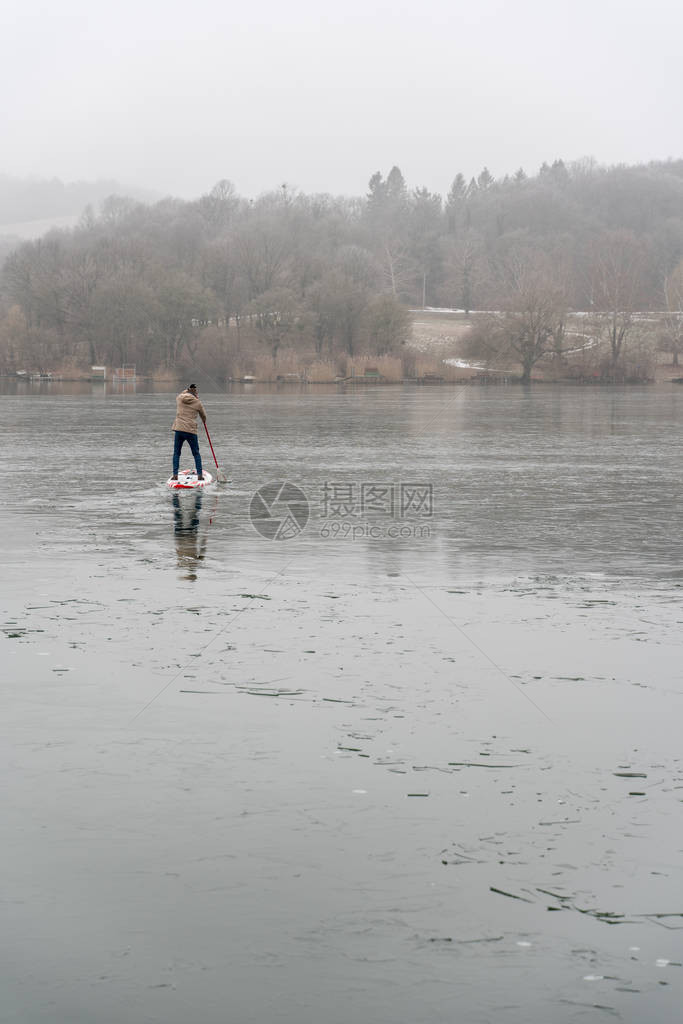站在冰湖上立式桨板上的男人图片