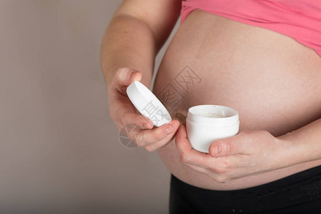 年龄在30至35岁之间的年轻怀孕妇女将皮肤奶油护理贴近肚图片