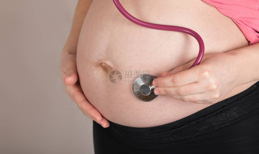 怀孕年龄在30至35岁之间的年轻孕妇用听诊器图片