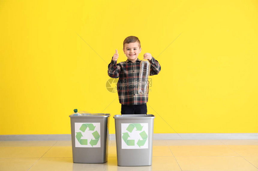 小男孩把垃圾扔进靠近彩色墙的垃圾桶里图片