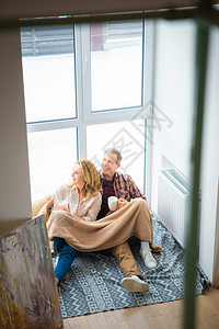 幸福的情侣坐在大窗户边的地板上图片