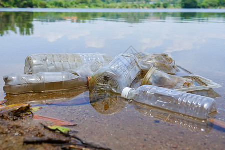 在湖中不当处置不可生物降解的聚氯乙烯杯和瓶子的不良恶习图片