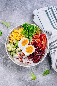 健康的素食午餐碗牛油果鸡蛋红豆番茄萝卜玉米绿叶蔬菜沙拉具体的背景顶视图片