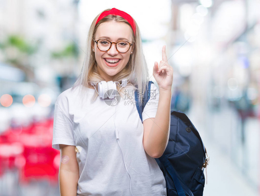 带着眼镜和背包的金发年轻女学生在孤立的背景中与成功的想法指手画脚图片