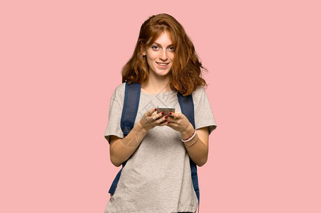 红发青年学生通过粉红色背景的手机传递讯息info图片