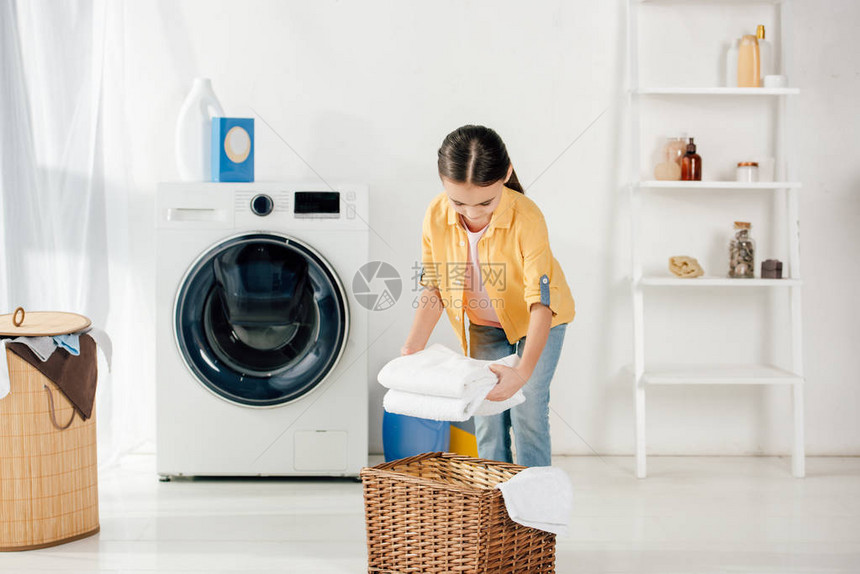 穿着黄色衬衫的孩子靠近洗衣机图片