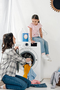 身穿粉色T恤的女儿坐在洗衣机上图片