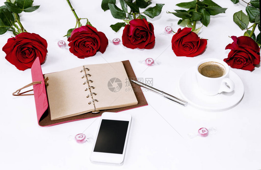 笔记本上写着一支笔一部电话和一束红玫瑰甜点和一杯咖啡的花束图片