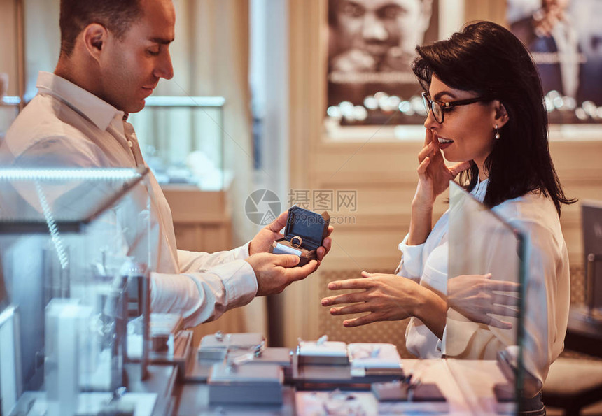 穿着优美衣服的男和女友在豪华珠宝店里图片