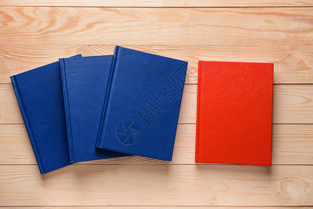 木制背景中的蓝色书籍中的红色书籍独特概念图片
