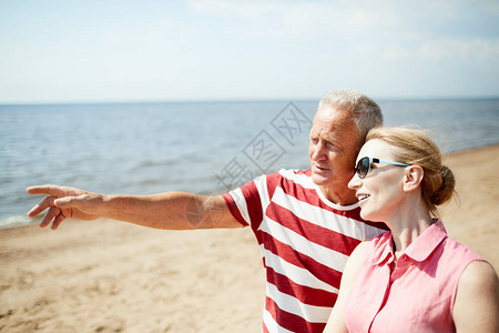 高年男子在向妻子展示离海滩很远的东西时指图片