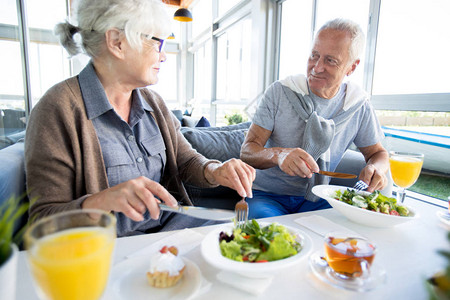 现代老年夫妇在度假咖啡馆享受午餐和聊天的长者肖像Por图片