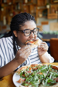 饿女人在餐盘上咬好吃的比萨饼午图片