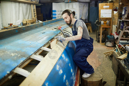职业造船工在船舶建造中锤击背景图片