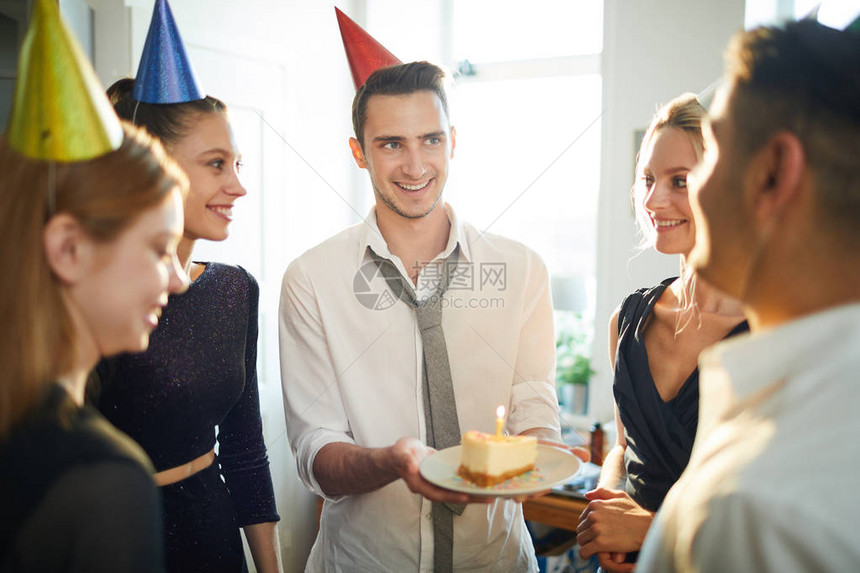 戴着生日帽子的快乐男人给他的一个朋友盘子一块蛋糕图片