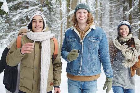 四个无忧虑的年轻人在度假期间在冬季森林玩乐时奔向镜头的腰部肖像图片