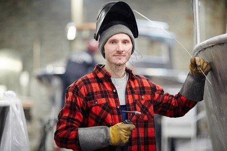 焊接面罩手套和工作服的青年焊接员图片