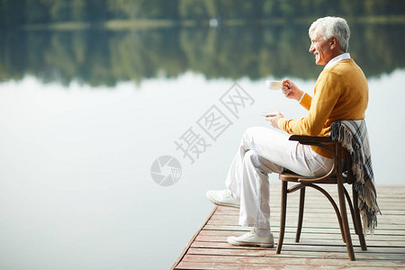 快乐放松的英俊老人穿着时髦的衣服坐在旧椅子上图片