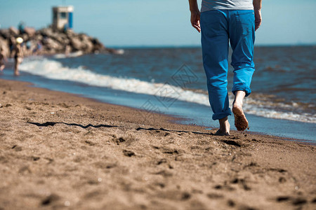 赤脚男子在湿沙上沿海岸线移动图片
