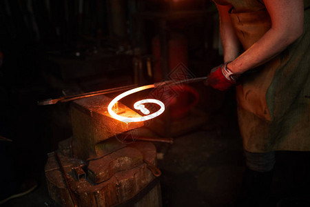铁匠在铁匠场工作时将热熔融金属螺旋体图片