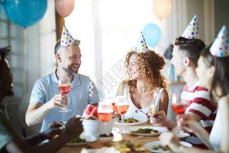 朋友们生日快乐坐在节庆的桌边祝图片