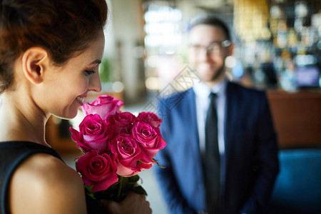 欢乐的黑发女人看着一帮浪漫的粉红玫瑰图片
