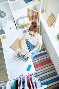 年轻的创意商业女青年坐在笔记本电脑前的办公桌旁图片