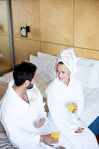在浴袍中快乐的一对年轻夫妇坐在酒店房间的床上图片