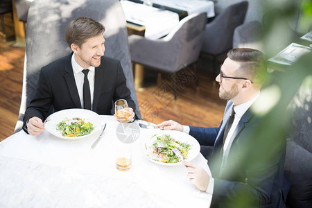 两个年轻的商业伙伴坐在餐厅的桌边图片