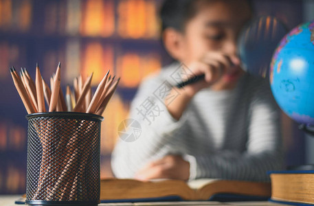 奋笔勤书木制桌上的铅笔和亚洲儿童勤背景
