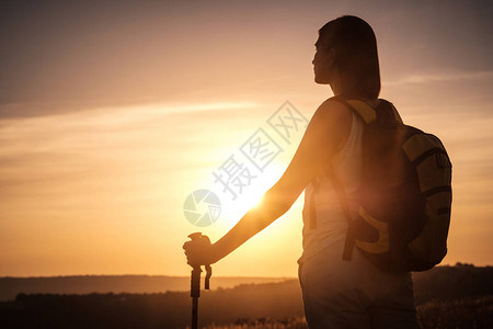 剪影徒步旅行者女人背着包和登山杖追踪图片