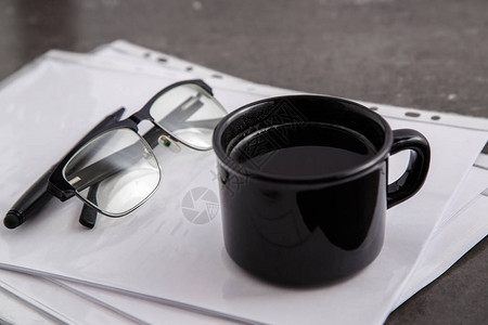 灰色大理石背景上的文件上的黑色咖啡和黑色钢笔图片